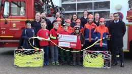 Auf dem Bild sind zu sehen: Vordere Reihe: 5 Kinder der Bambini-Feuerwehr. Mittlere Reihe: 5 Kinder der Jugendfeuerwehr. V.l.n.r.: Stefanie Patz (Leiterin Bambini-Feuerwehr), Ralf Weiler (stellv. Wehrführer), Sven Senko (Wehrführer), Barbara Weiler, Susanne Streit, Nils Becker, Volker Häp und Tyrone Winbush (Vorstandsmitglied Bürgerdienst e.V.)